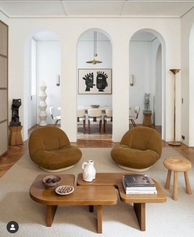 Salon moderne avec des fauteuils bruns , une table basse en bois et des œuvres d'art sur les murs.