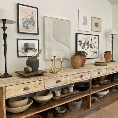 Mobilier en bois avec des objets en céramique, lampes et œuvres d'art sur le mur.