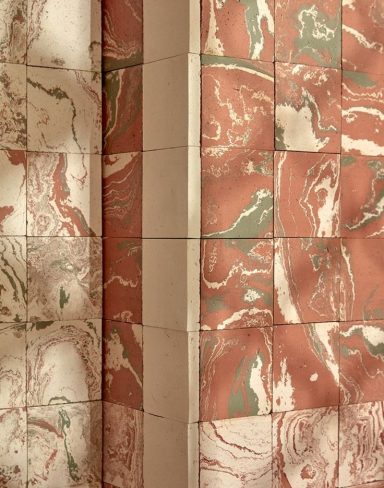 Mur décoratif en carreaux marbrés de nuances rose et vert.