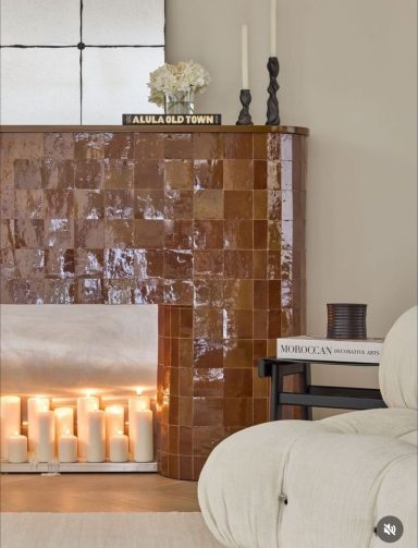 Cheminée en carrelage marron avec bougies et décor moderne dans un intérieur lumineux.