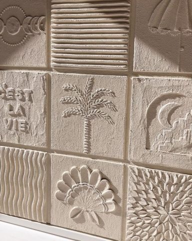 Carreaux en plâtre avec motifs variés, dont un palmier et des vagues stylisées.